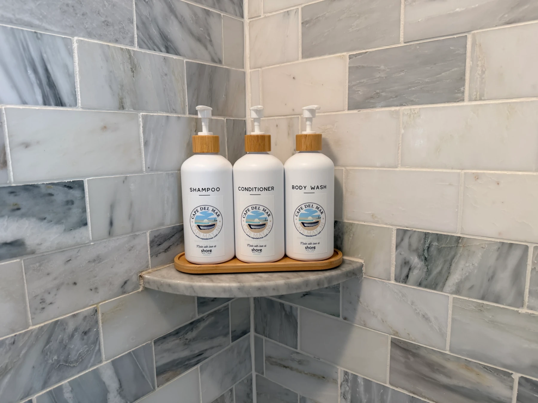 Bathroom shelf with white amenity bottles and marble tile at Cape Oar luxury property in Cape May