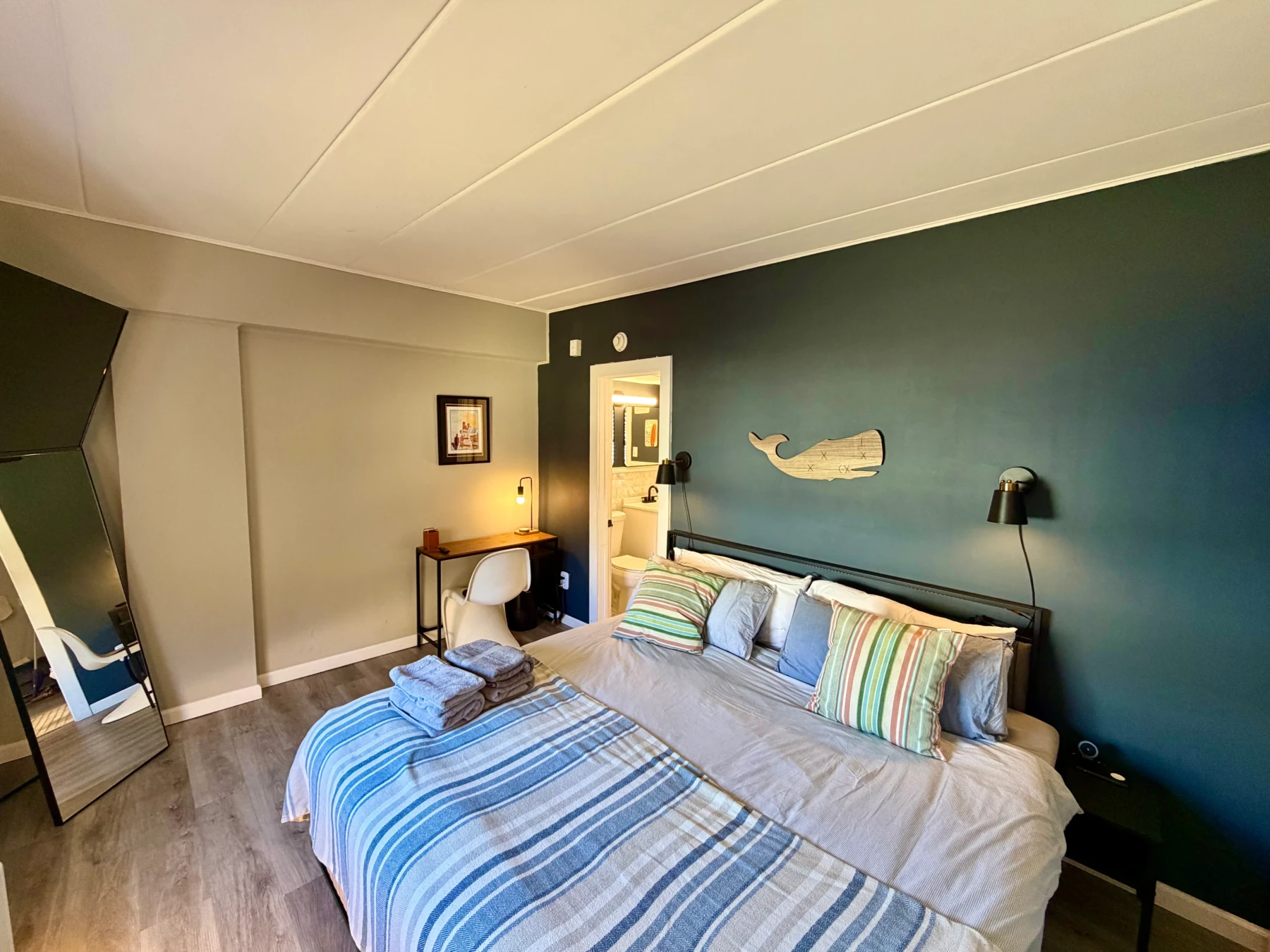 Master bedroom with dual beds, teal accent wall, and nautical decor in Cape May coastal condo