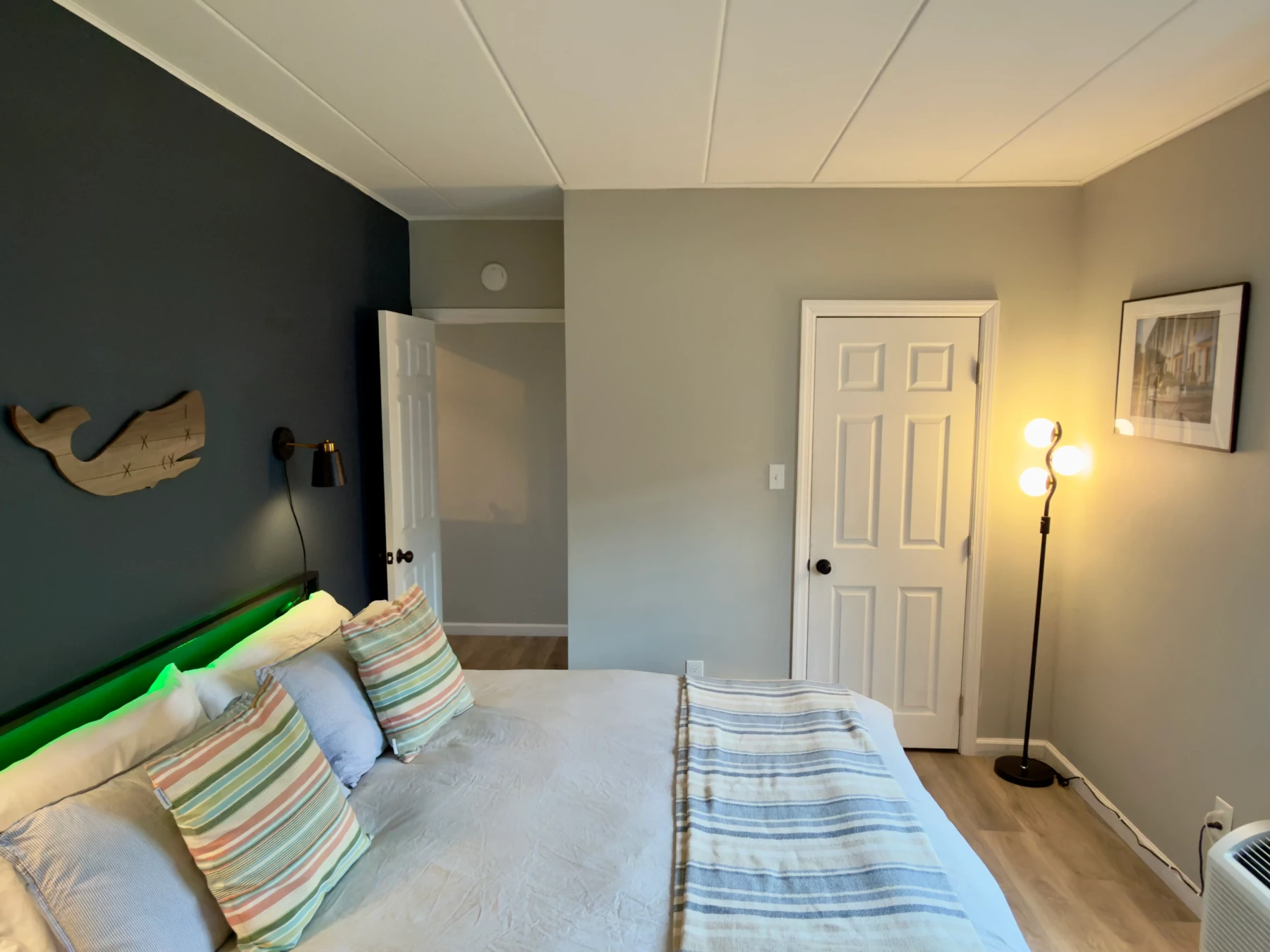 Nautical themed bedroom with green bed frame, striped pillows, whale wall decor at Cape del Mar