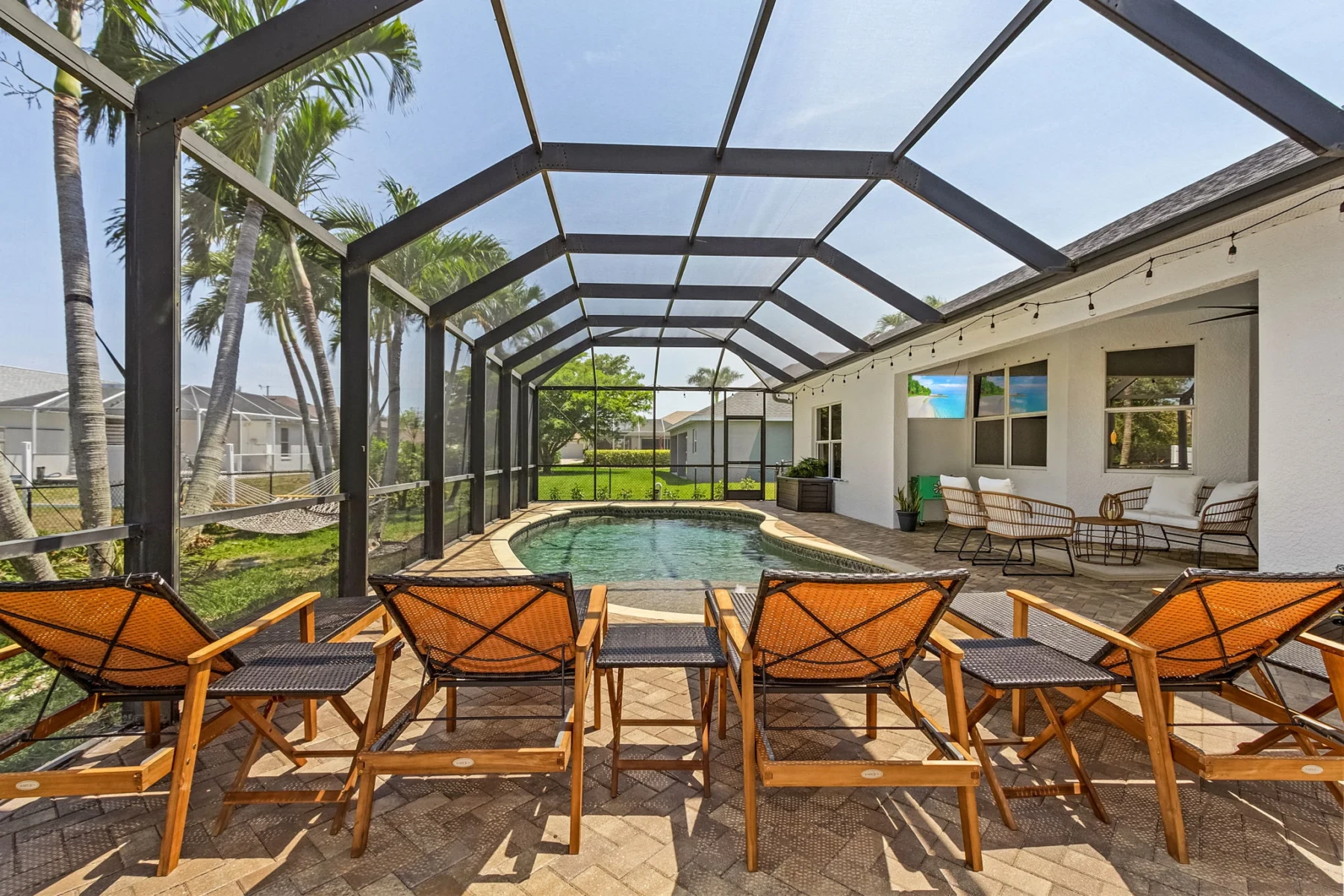 Private pool with screened lanai, lounge chairs and palm trees at Cape Pelican