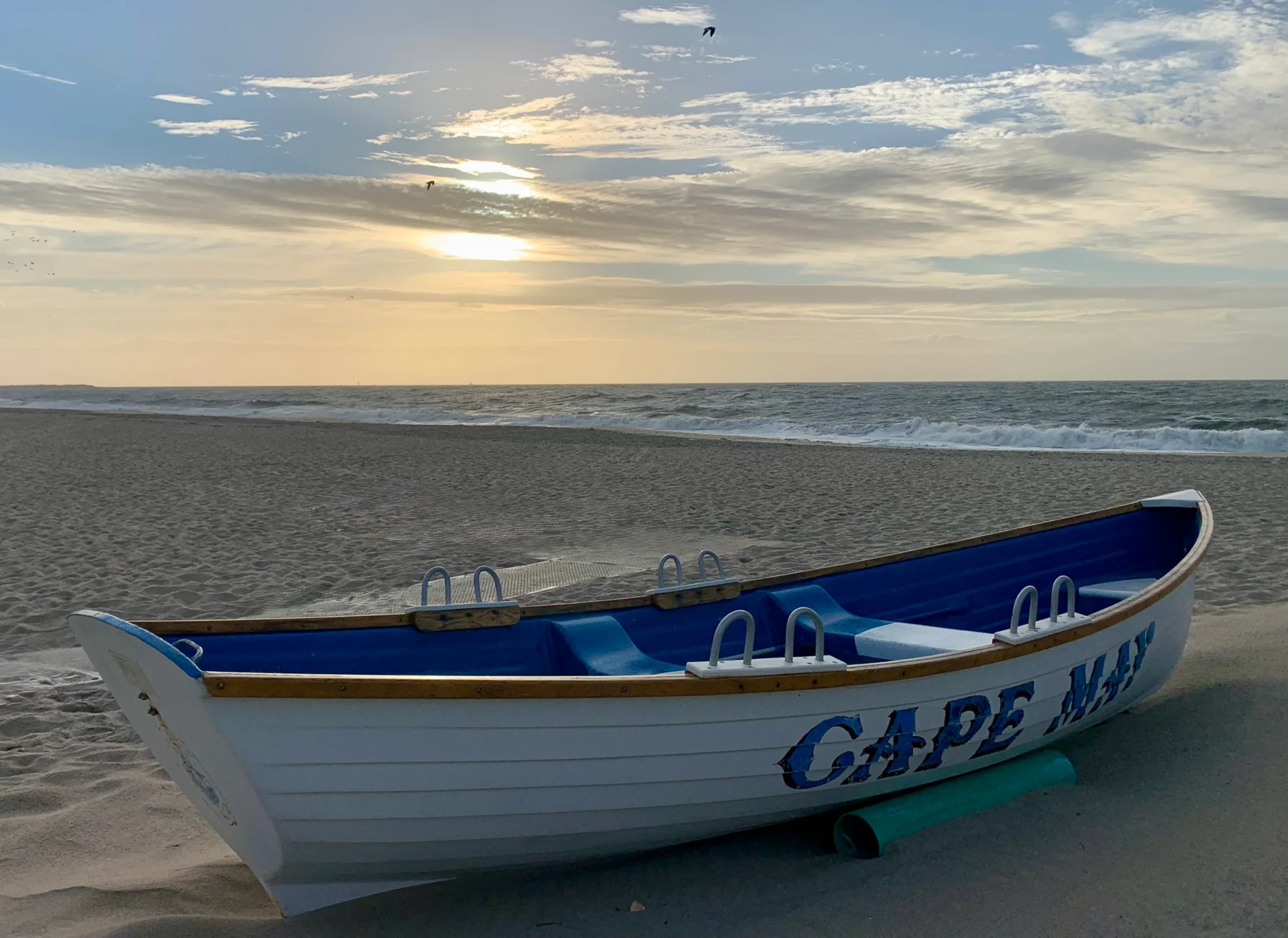 Fishing boat on golden sand beach with ocean waves and sky at Cape May vacation rental
