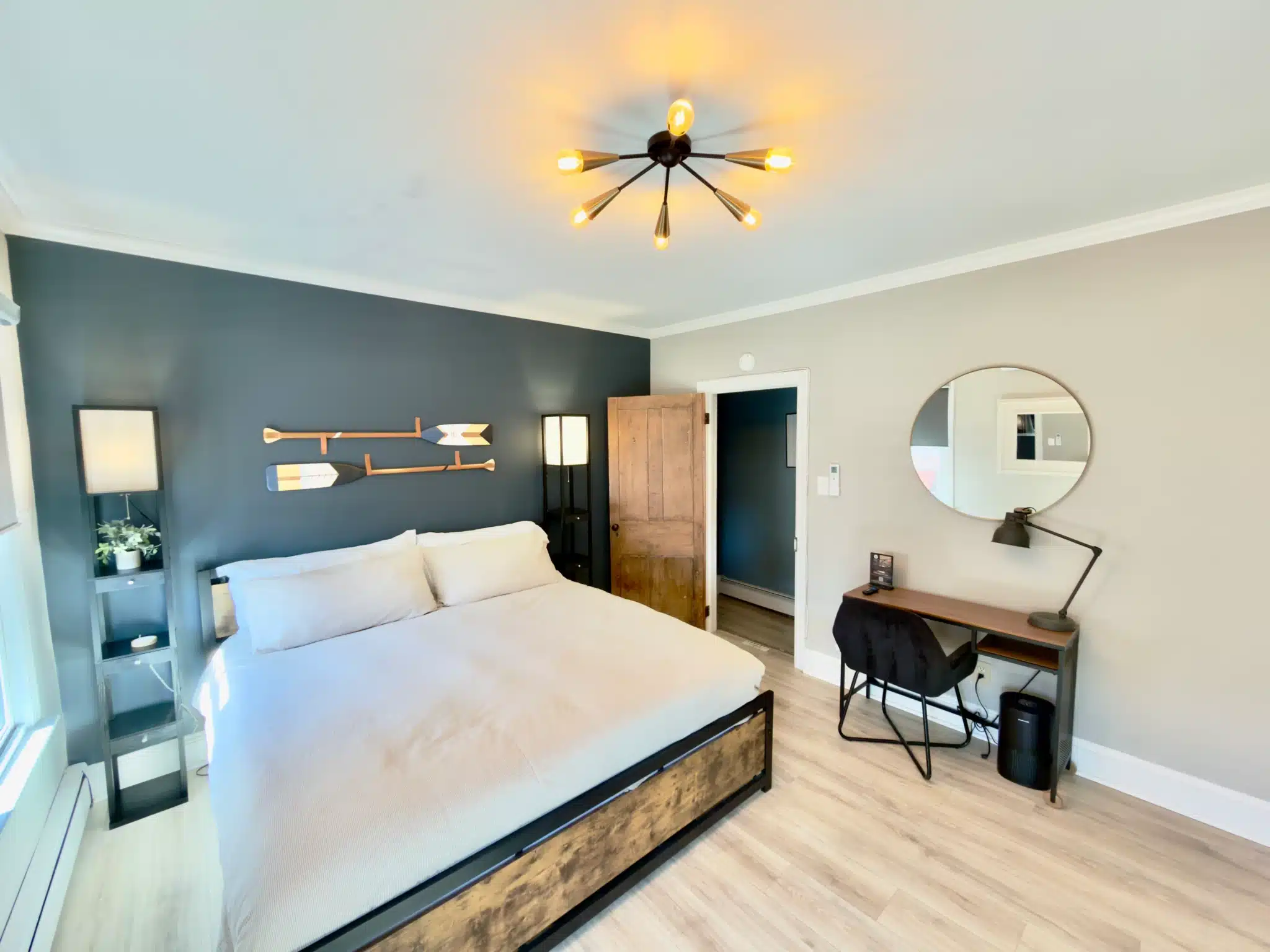Modern coastal bedroom with queen bed, teal accent wall, nautical art, and workspace in Cape May vacation rental