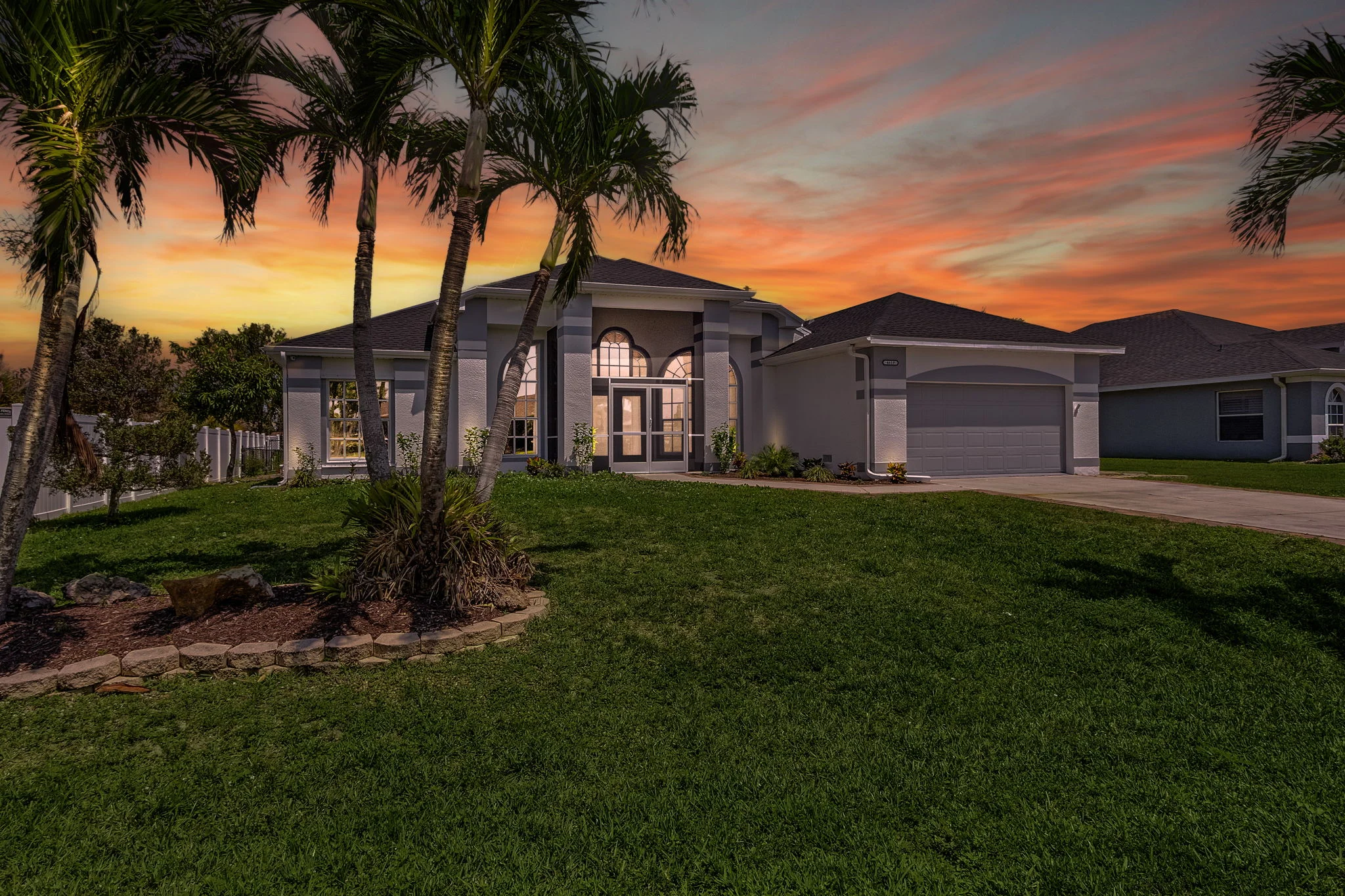 Modern Florida home exterior at sunset with ocean view seating area and palm landscaping in Cape Coral